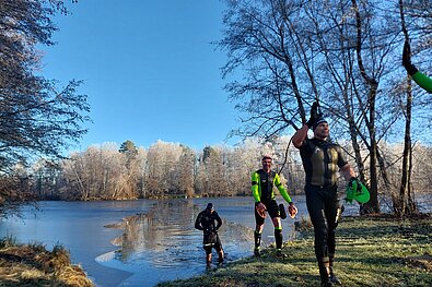 Bild von 3 Teilnehmern, die aus dem Fluss kommen